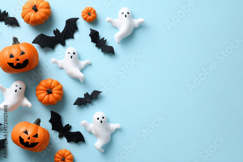 Halloween background with pumpkins, bats, and ghosts on a light blue surface, offering copy space for text or design.