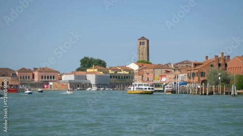 Boats sail along the waterfront of murano, italy on a sunny day