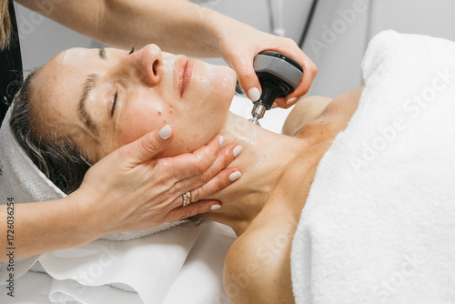 Photos Woman receiving RF lifting treatment for facial rejuvenation, with a professiona