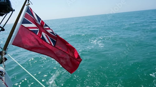 30 JUN 2025 - Solent, UK - The British Ensign Flag on the back of a sailing yacht flapping in the wind.