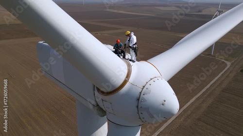 Aerial view of rope access technicians performing maintenance on top of a wind turbine nacelle. Industrial safety, renewable energy inspection, and clean energy service work from above.

