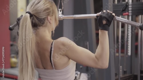 Upper Body Workout: Focused female athlete using a cable machine for seated lat pulldown