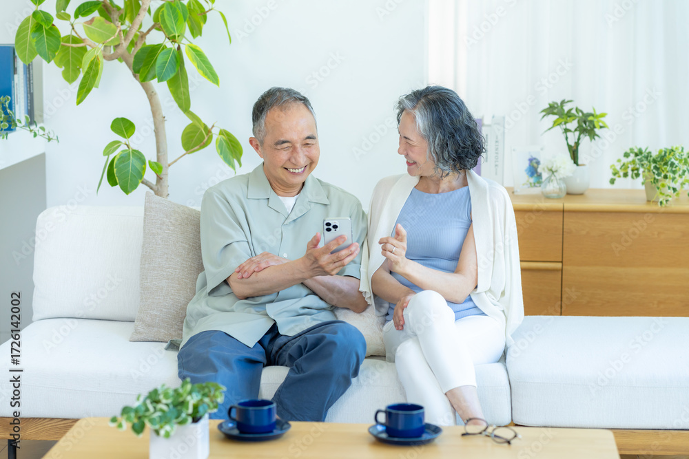 Fototapeta premium リビングでスマホを見るシニア夫婦
