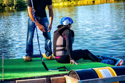 A woman getting ready for wakeboarding on sea on summer day in jacket.
