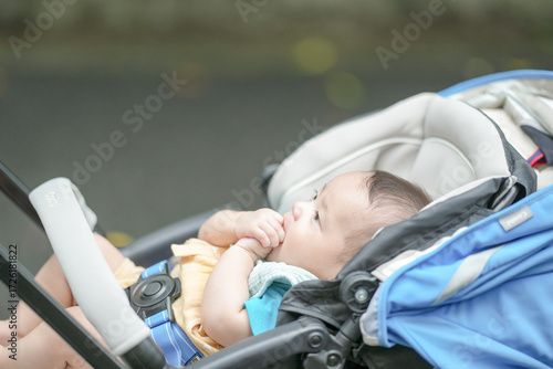 Tableau sur toile A baby is sitting in a stroller and is holding onto a towel