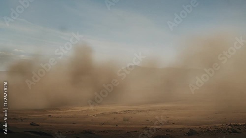 A heavy vehicle traverses a dusty landscape, showcasing industrial power.