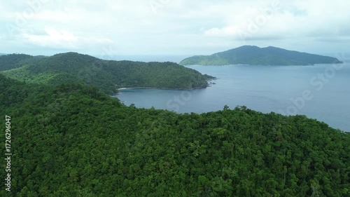 Linear drone flight over lush island jungle toward secluded coves near Port Barton, San Vicente, Palawan. Hidden pocket beaches and forested hills meet a calm blue sea under soft daylight.