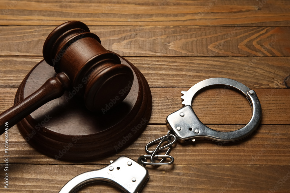 Obraz premium Handcuffs with judge's gavel on wooden background, closeup