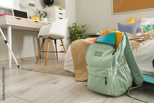 Backpack with notebooks on floor in children's bedroom