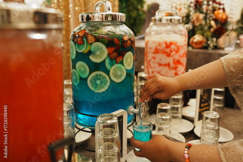 A person is pouring blue drink with fruits.