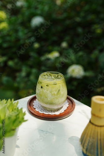 A glass of iced matcha latte on a wooden plate.