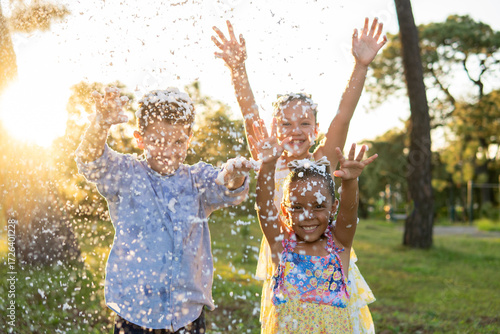 tres niños felices jugando y disfrutando de su infancia e inocencia alegres y contentos en un parque al aire libre en un hermoso atardecer jugando con espuma 