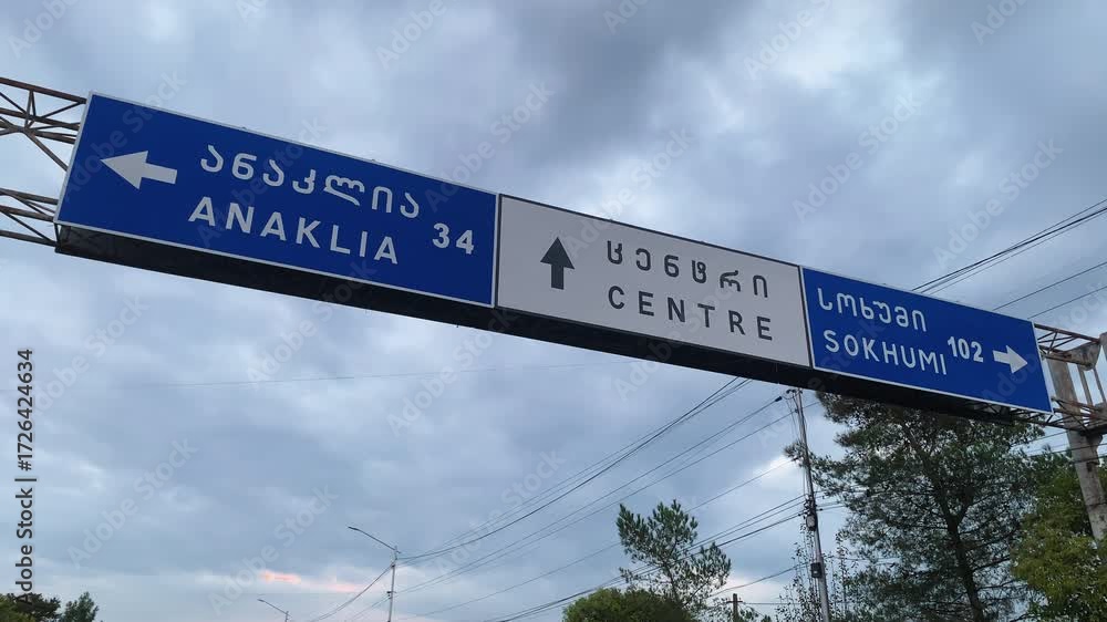 A highway sign points towards Anaklia and Sokhumi. Captures themes of travel, direction, and new destinations on a road trip through Georgia.
