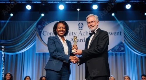 A woman in a blue suit receiving an award from a man in a black suit.