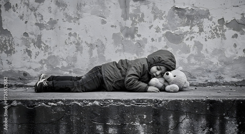Sad child lying down with a teddy bear in black and white