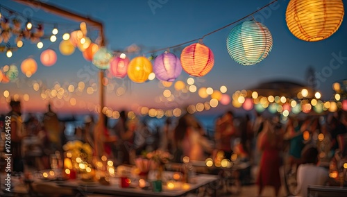 Festive outdoor gathering at sunset.  Colorful lanterns and string lights illuminate a beach party.  Blurred figures of people