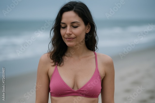 Young Woman Wearing Pink Bikini Top Standing on Beach with Ocean in Background