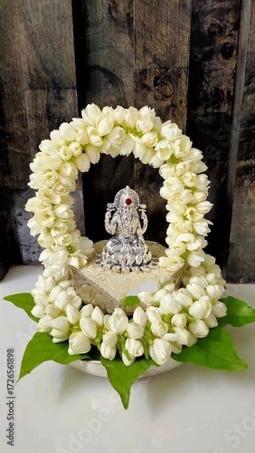 a silver idol of Goddess Lakshmi adorned with a beautiful garland of white jasmine flowers, arranged in an arch