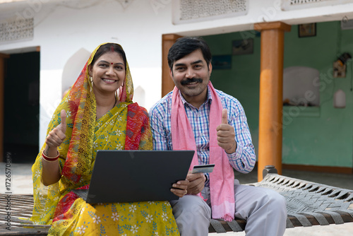 Fotografía Indian happy rural middle class couple working on laptop in village with debit c