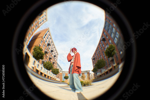 Foto Fish eye view of Young Caucasian woman standing outdoors between tall buildings,