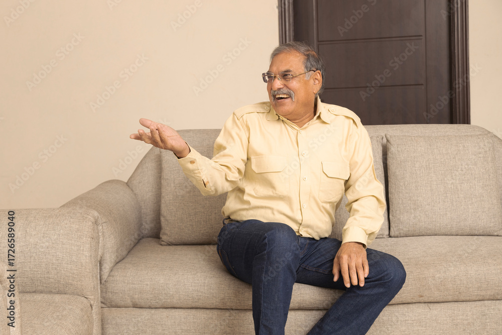 Fototapeta premium Portrait of a indian happy Senior age man sitting at home relaxing on sofa having coffee