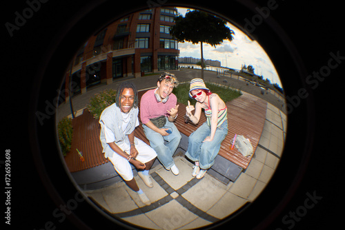 Schilderij op canvas Group of three teenagers, Black, Caucasian male, female, sitting on outdoor benc