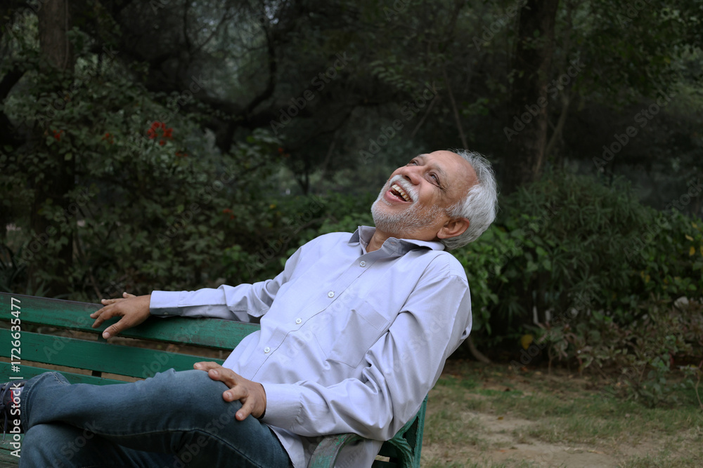 Obraz premium Indian happy senior man feels freedom, fun and spending leisure time while looking at the camera at the park after retirement
