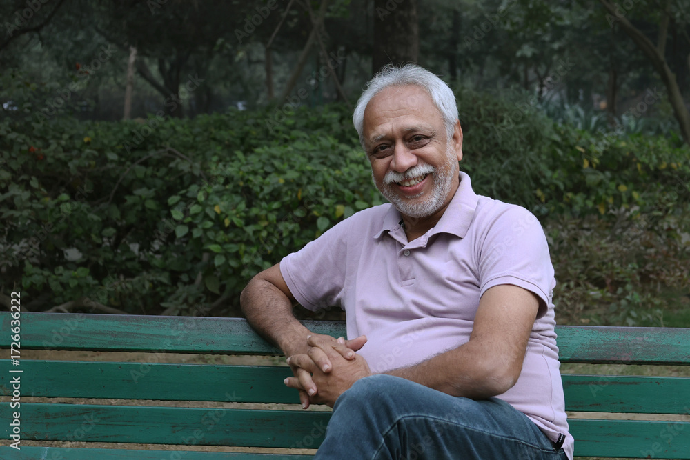 Fototapeta premium Indian happy senior man feels freedom, fun and spending leisure time while looking at the camera at the park after retirement