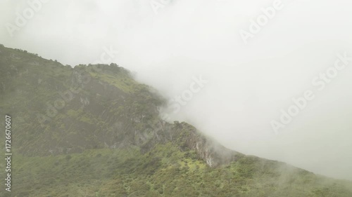 A video green mountain ridge, covered in vibrant vegetation, with fluffy clouds drifting across it