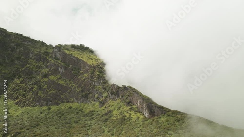 A video green mountain ridge, covered in vibrant vegetation, with fluffy clouds drifting across it