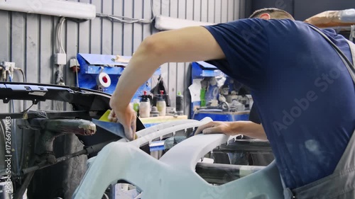 Specialist carries out preparatory actions during repairs. Master uses special approach to clean surface of material working in service center hall