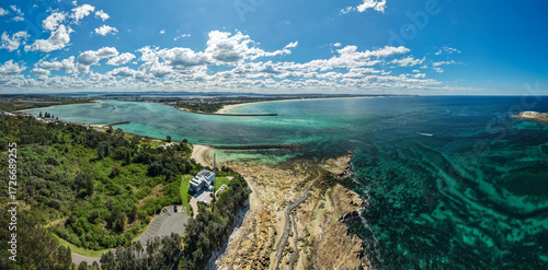 Aerial view of vibrant turquoise waters meet rocky shores and lush green headlands, revealing the scenic beauty of the coast, Swansea, New South Wales, Australia.