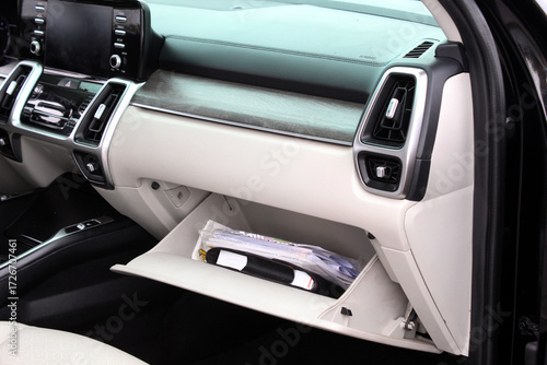 Car glove compartment with folder documents. Open glove compartment in modern car interior with beige panels, black dashboard, wood trim, and stored documents inside. Service documents.