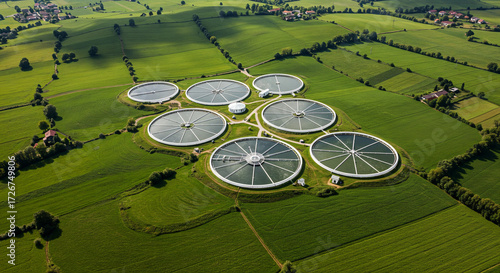 Wallpaper Mural Aerial view of a wastewater treatment plant with circular tanks surrounded by green fields and scattered trees. Torontodigital.ca