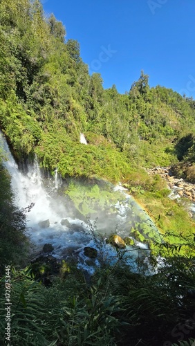 Beautiful Saltos Ojos del Huishue waterfall in southern Chile, surrounded by lush green forest and rugged rocks, a stunning natural escape.