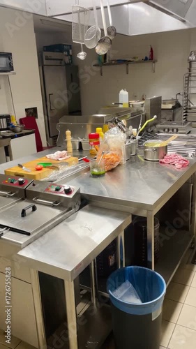 Interior of professional kitchen in public catering, showing industrial equipment, appliances, and work surfaces. Food service infrastructure, reflecting organized preparation of meals in restaurants.