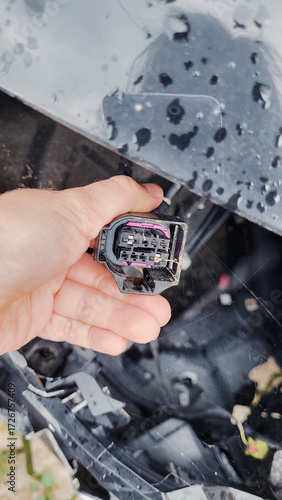 Hand holding dusty cobweb-covered car wiring connector close up