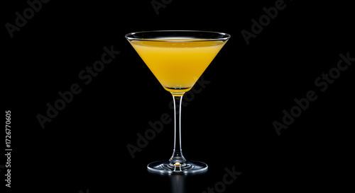 Yellow cocktail in a martini glass on black background -  