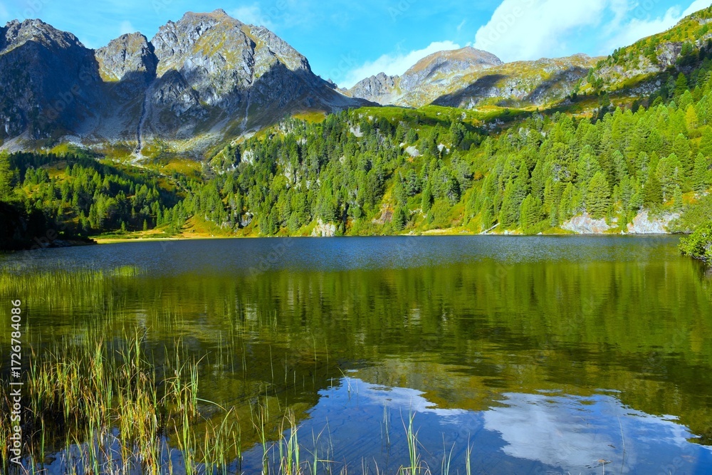 Fototapeta premium View of Unterere Zwiefler lake with a reflection in the water bellow the mountain peaks in Sölktäler nature park in Niedere Tauern, Styria, Austria