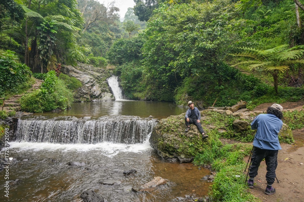 Obraz premium Photographer Picturing Adventurous Travelers In Serene Beauty Of Waterfall