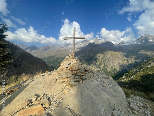 Summit view featuring the Croce di Arolley, a wooden cross mounted on a pile of rocks at high altitude in Valsavarenche, within the Gran Paradiso National Park, Aosta Valley, Italy
