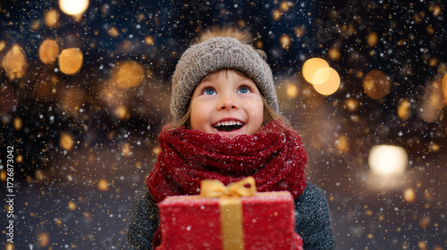 Happy little girl with a Christmas present feeling joyful in the winter snow