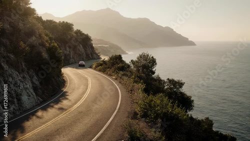 Scenic coastal road winding along a cliff overlooking the ocean at golden hour
