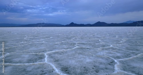 Geometrical crust created on the surface of the Bonneville Salt Flats, Utah, USA. Drone flight approaching the mountains silhouettes at backdrop.