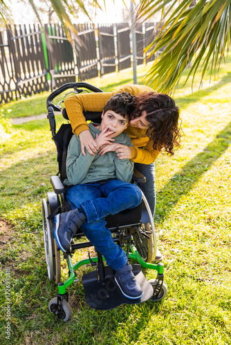 Mother hugging son with disability in wheelchair in park
