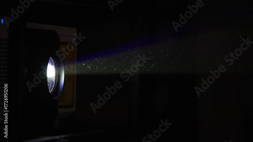  Film projector illuminating the dark cinema with bright light, side view. Projector illuminating a dark space with vibrant light beams at an art installation.