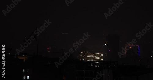 Wallpaper Mural Tehran city skyline at night with Iranian flag visible in the foreground. Lightning from a thunderstorm illuminates the hazy sky, creating a dramatic and cinematic urban night atmosphere. Torontodigital.ca