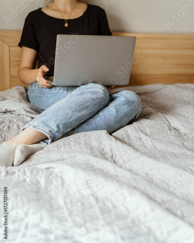 Faceless woman using laptop on bed, casual and candid aesthetic