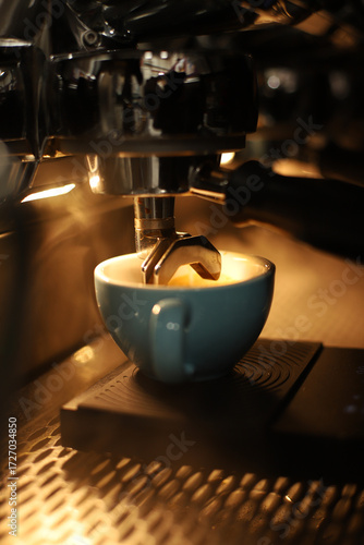 A barista makes a cappuccino with beautiful latte art against the backdrop of a coffee machine with bright background lighting.