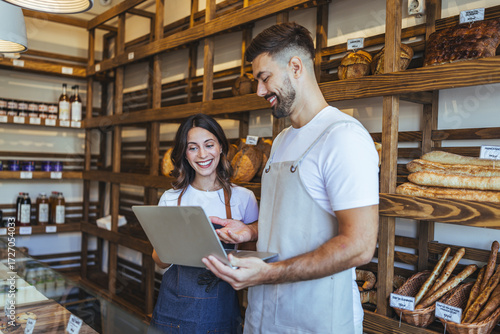 Friendly Bakery Staff Showing Tablet To Customer In Cozy Bread Shop